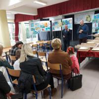 Na scenie na tablicach wyeksponowane są prace konkursowe, na scenie wójt i dyrektor szkoły, przed sceną siedzi kilkanaście osób dorosłych i dzieci