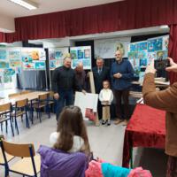 Na scenie na tablicach wyeksponowane są prace konkursowe, na scenie wójt i dyrektor szkoły i dwoje nauczycieli, którzy wręczają dzieciom nagrody