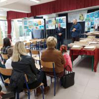 Na scenie na tablicach wyeksponowane są prace konkursowe, na scenie wójt i dyrektor szkoły i dwoje nauczycieli, którzy wręczają dzieciom nagrody