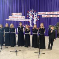 Sala gimnastyczna udekorowana fioletowymi zasłonami oraz napisami RADOSNA NIEPODLEGŁOŚCI gminny konkurs pieśni patriotycznych oraz Wolność kocham i rozumiem - wolności oddać nie umiem, zdjęcia występów konkursowych, wójta dyrektora szkoły, nauczycieli itp...