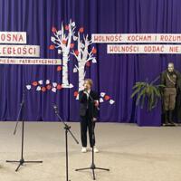 Sala gimnastyczna udekorowana fioletowymi zasłonami oraz napisami RADOSNA NIEPODLEGŁOŚCI gminny konkurs pieśni patriotycznych oraz Wolność kocham i rozumiem - wolności oddać nie umiem, zdjęcia występów konkursowych, wójta dyrektora szkoły, nauczycieli itp...