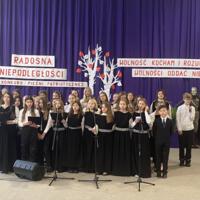Sala gimnastyczna udekorowana fioletowymi zasłonami oraz napisami RADOSNA NIEPODLEGŁOŚCI gminny konkurs pieśni patriotycznych oraz Wolność kocham i rozumiem - wolności oddać nie umiem, zdjęcia występów konkursowych, wójta dyrektora szkoły, nauczycieli itp...