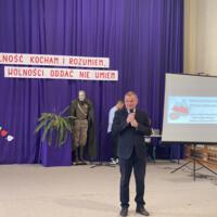 Sala gimnastyczna udekorowana fioletowymi zasłonami oraz napisami RADOSNA NIEPODLEGŁOŚCI gminny konkurs pieśni patriotycznych oraz Wolność kocham i rozumiem - wolności oddać nie umiem, zdjęcia występów konkursowych, wójta dyrektora szkoły, nauczycieli itp...