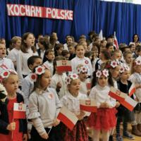 Obchody Narodowego Święta Niepodległości w Szkole Podstawowej w Marcinkowicach - dzieci na sali gimnastycznej wymachują biało-czerwonymi chorągiewkami
