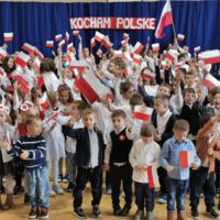 Obchody Narodowego Święta Niepodległości w Szkole Podstawowej w Marcinkowicach - dzieci na sali gimnastycznej wymachują biało-czerwonymi chorągiewkami
