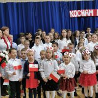 Obchody Narodowego Święta Niepodległości w Szkole Podstawowej w Marcinkowicach - dzieci na sali gimnastycznej wymachują biało-czerwonymi chorągiewkami