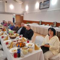 Bal seniora - przy stołach na których znajduje się poczęstunek i napoje siedzą seniorzy - sala jest elegancko przystrojona, niektórzy tańczą