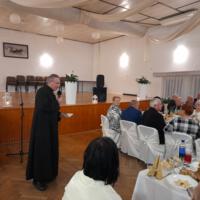 Bal seniora - przy stołach na których znajduje się poczęstunek i napoje siedzą seniorzy - sala jest elegancko przystrojona, niektórzy tańczą