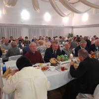 Bal seniora - przy stołach na których znajduje się poczęstunek i napoje siedzą seniorzy - sala jest elegancko przystrojona, niektórzy tańczą