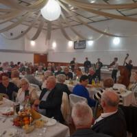 Bal seniora - przy stołach na których znajduje się poczęstunek i napoje siedzą seniorzy - sala jest elegancko przystrojona, niektórzy tańczą