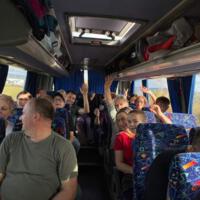 Zdjęcie uczestników w autokarze - niektórzy z nich mają wyciągnięte ręce