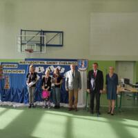 Wspólne zdjęcie zawodników z Wójtem i przewodniczącym Komisji Kultury Andrzejem Tyrklem oraz dyrektorką szkoły, zawodnicy są udekorowani medalami oraz trzymają w rękach nagrody, w tle tablica z napisem Mistrzostwa Gminy Chełmiec 