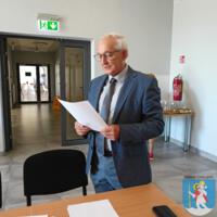 Spotkanie Gminnej Rady Seniorów, przewodniczący ubrany w garnitur czyta dokument.