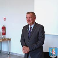 Spotkanie Gminnej Rady Seniorów, wójt ubrany w garnitur stoi za stołem, ma złożone ręce
