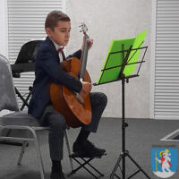 Młody chłopak elegancko ubrany gra na gitarze