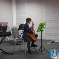 Młody chłopak elegancko ubrany gra na gitarze