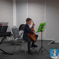 Młody chłopak elegancko ubrany gra na gitarze