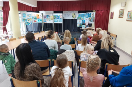 Na scenie na tablicach wyeksponowane są prace konkursowe, przed sceną siedzi kilkanaście osób dorosłych i dzieci