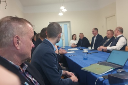 Walne Zebranie Stowarzyszenia „Sądecki Obszar Funkcjonalny”. - kilkanaście osób w garniturach siedzi przy stole - na stole filiżanki, laptop, dokumenty